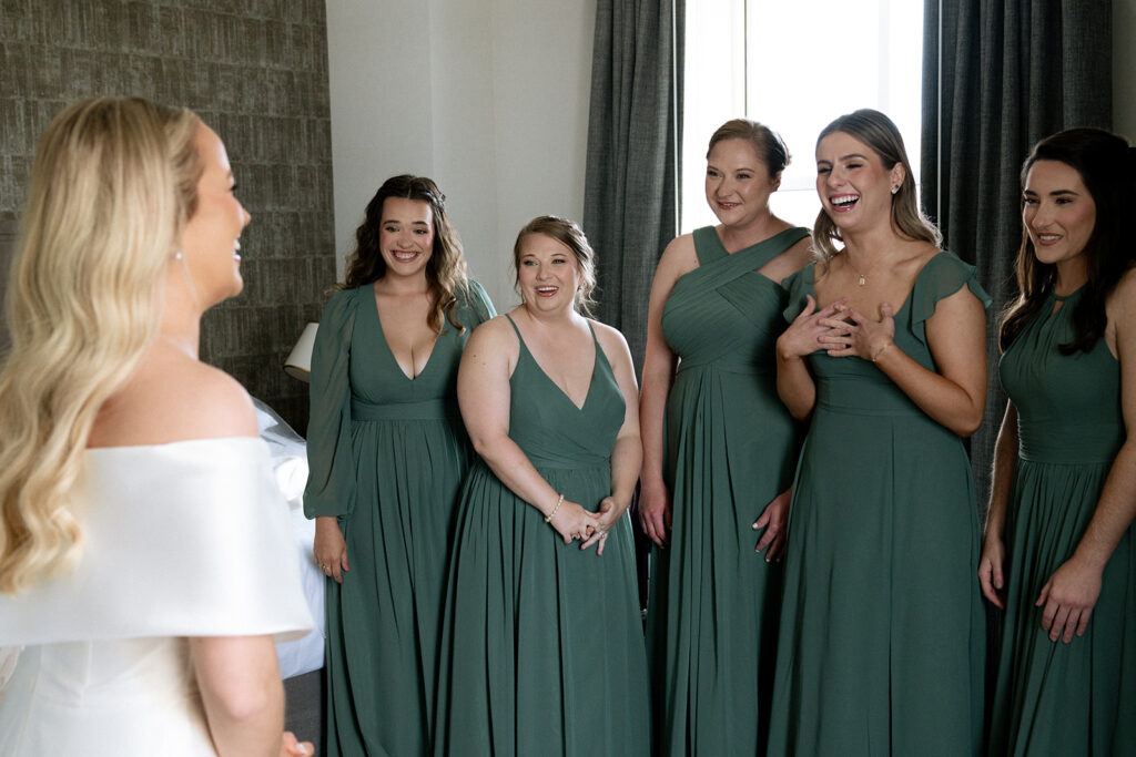 bridesmaids happy seeing the bride in her wedding dress