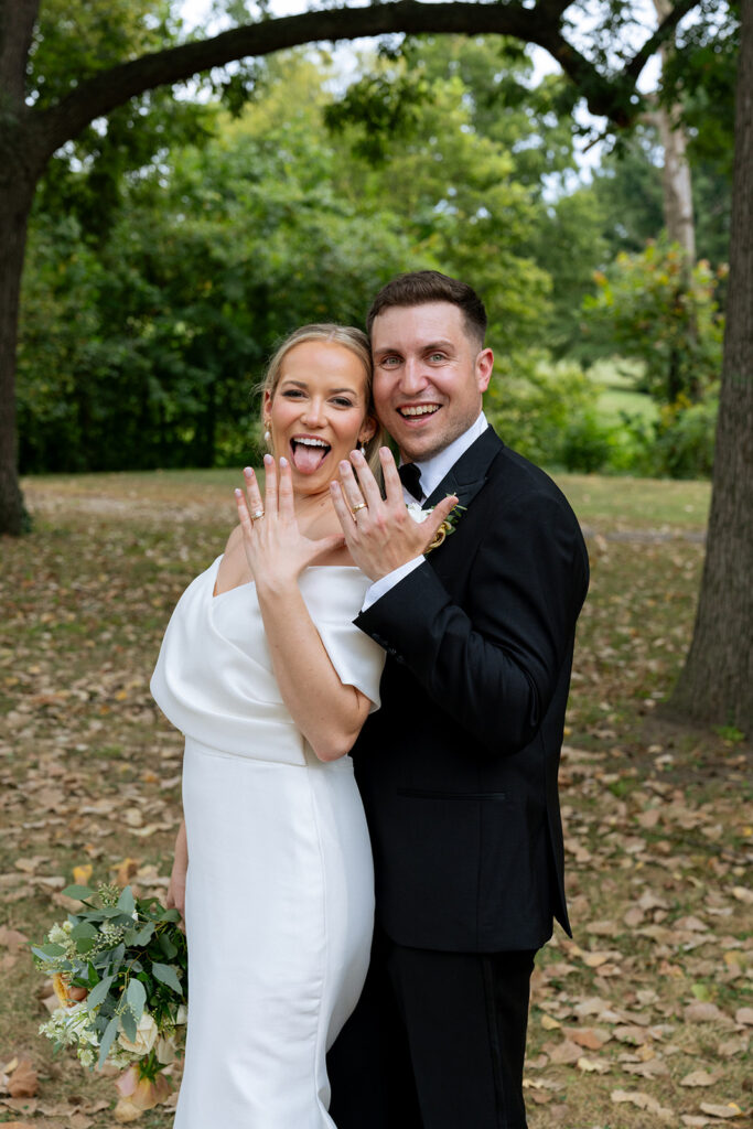 fun portrait of the bride and groom showing their wedding rings