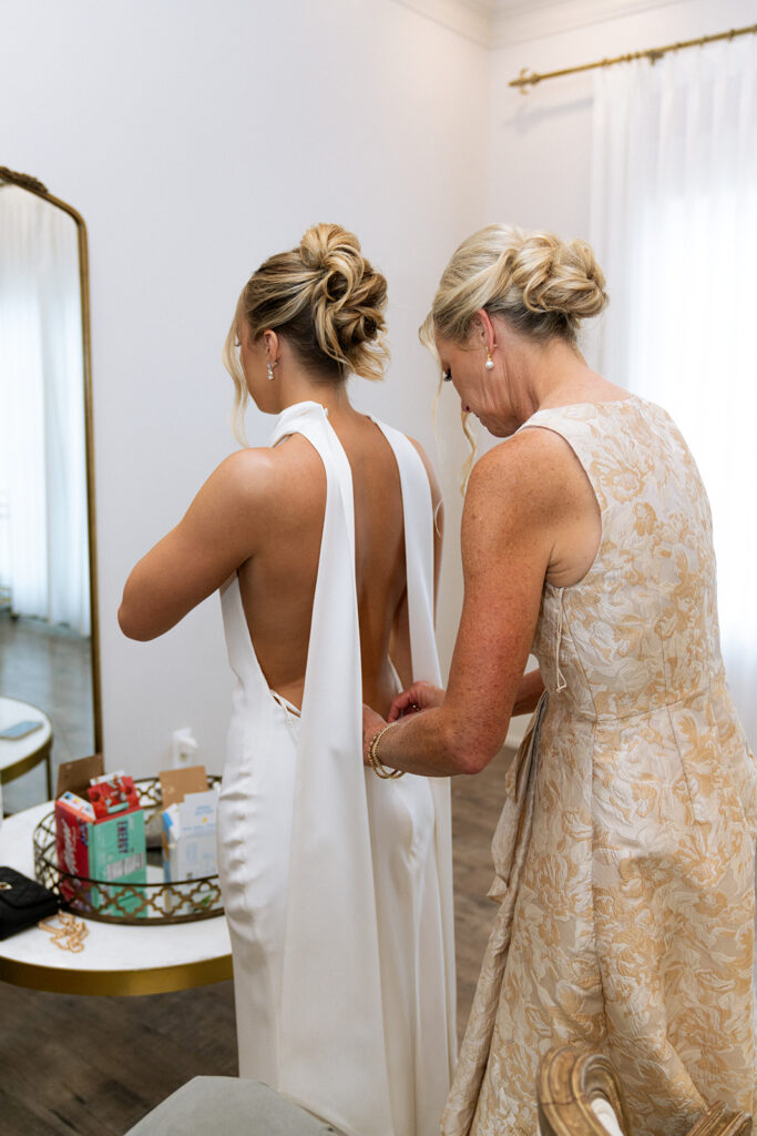 mother of the bride helping her with the wedding dress