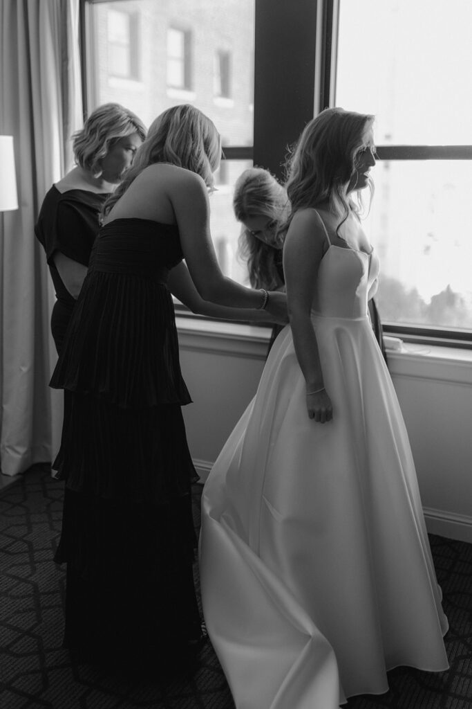 mother and sisters of the bride helping her with the wedding dress