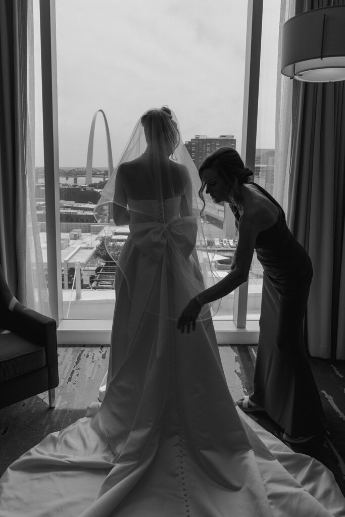 mother of the bride helping her with the wedding dress