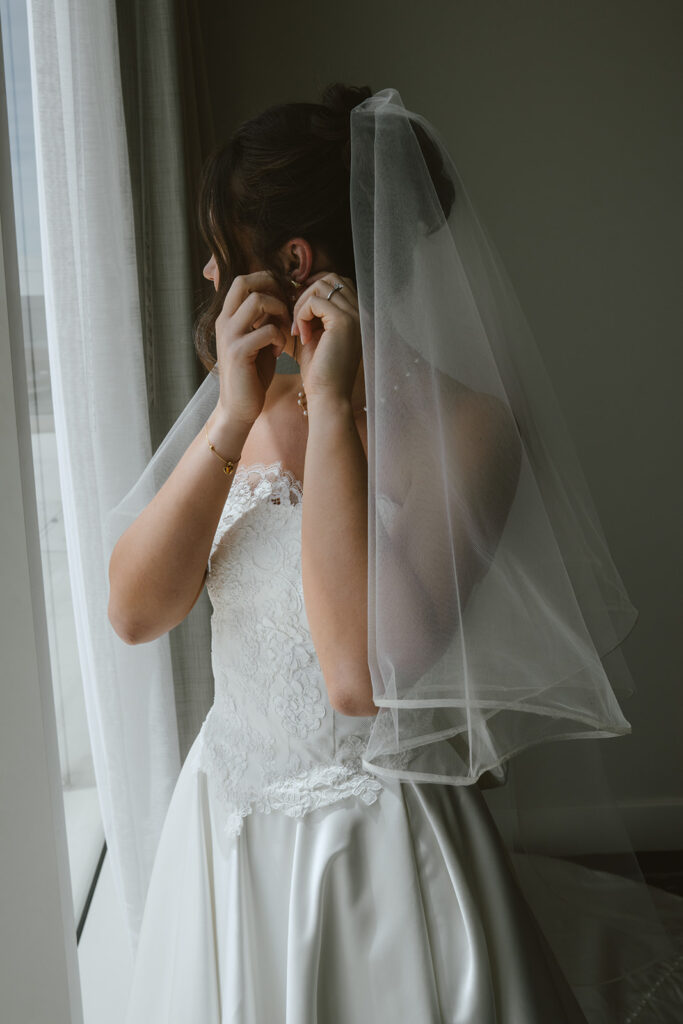 bride putting on her jewelry before heading to her ceremony 