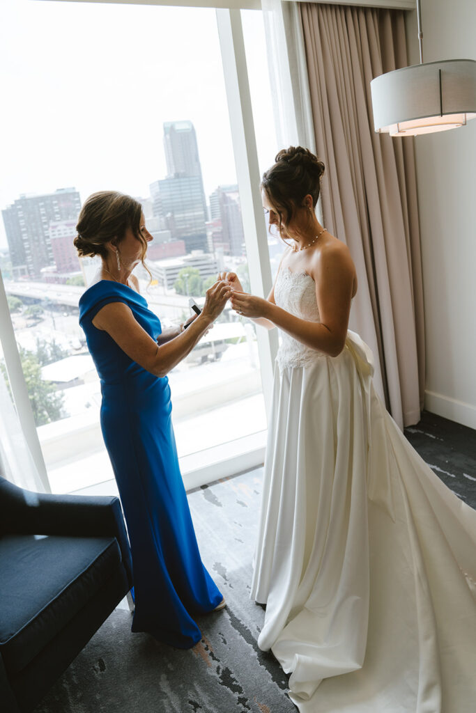 Mother of the bride helping her with the wedding dress