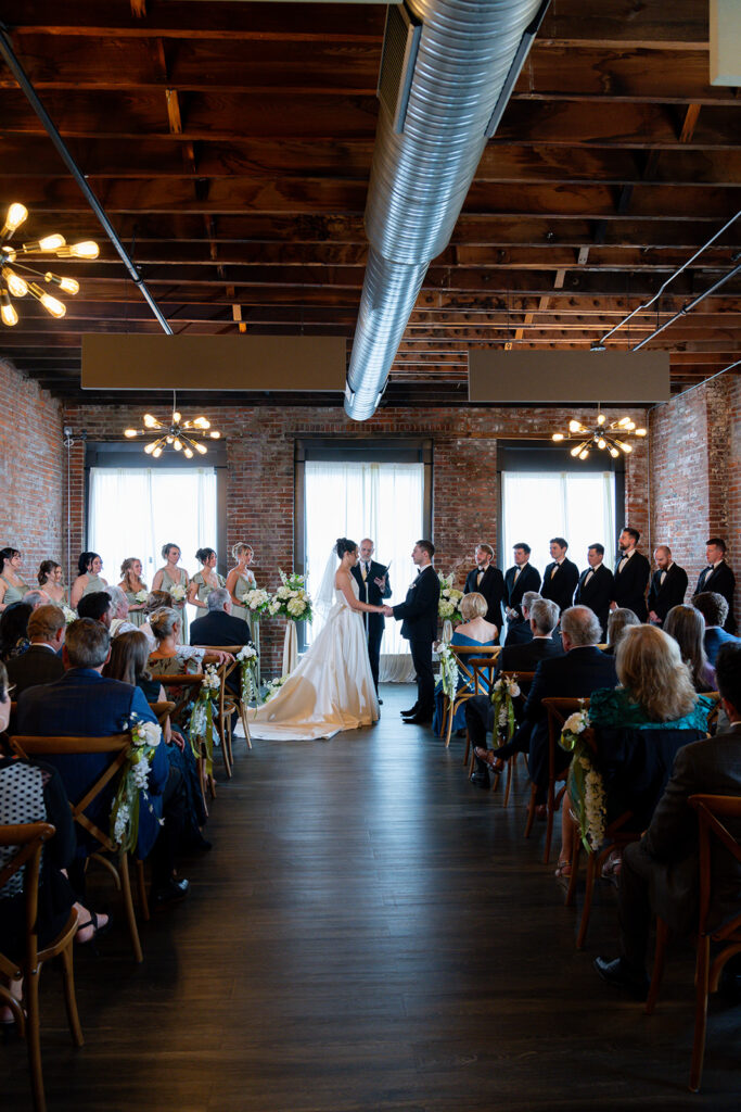 Picture of the bride and groom holding hands during their wedding ceremony