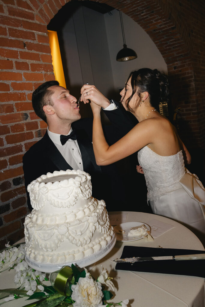 Cute picture of the bride and groom, trying their wedding cake