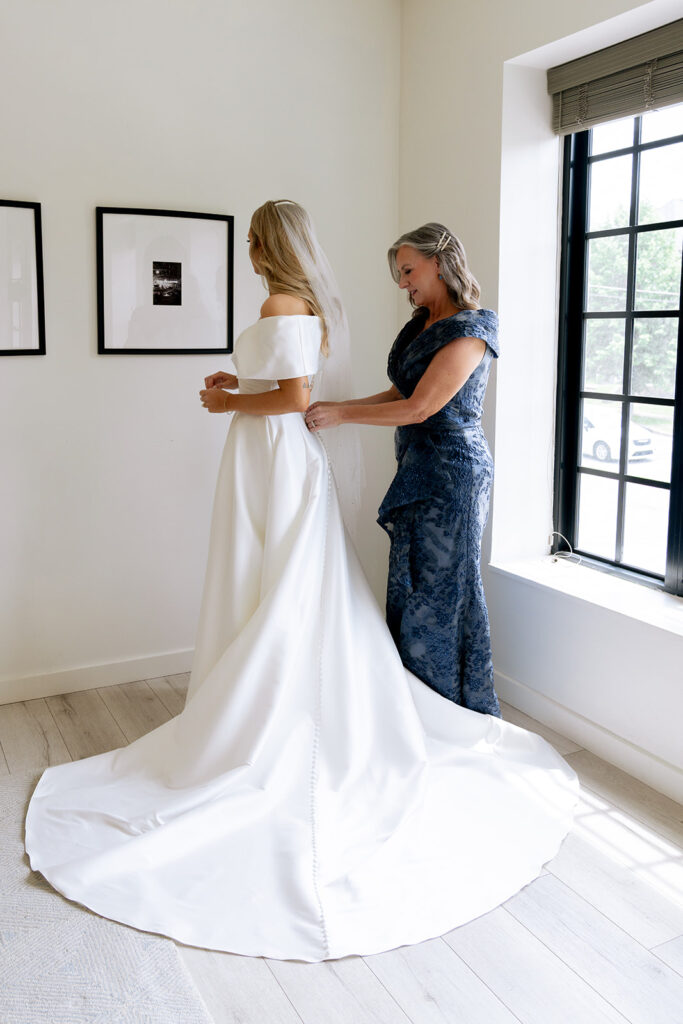 mother of the bride helping her with her wedding dress