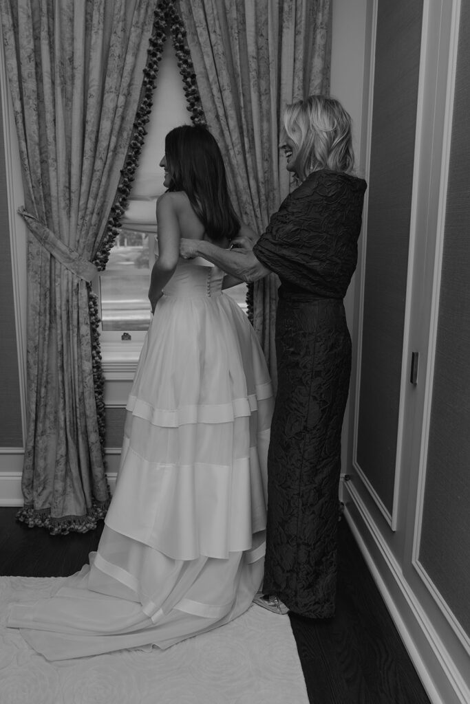 mother of the bride helping her with the wedding dress