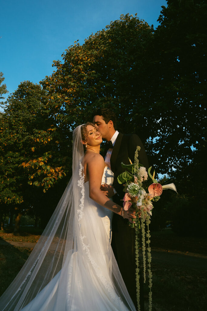portrait of the groom kissing the bride on the cheek
