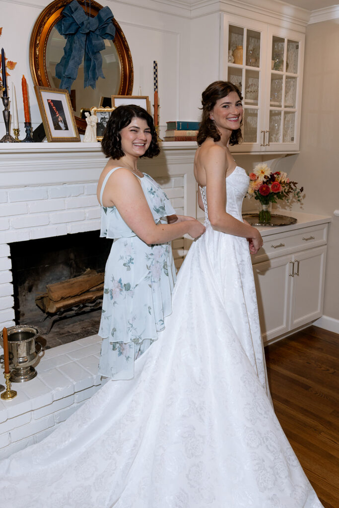 sister of the bride helping her with her wedding dress