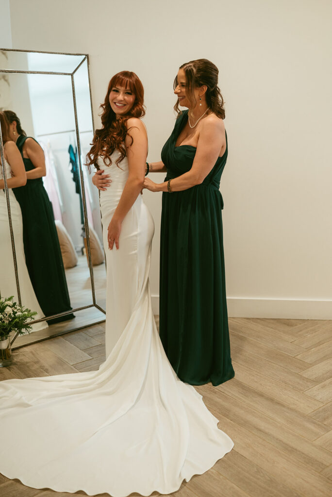 mother of the bride helping her with her wedding dress