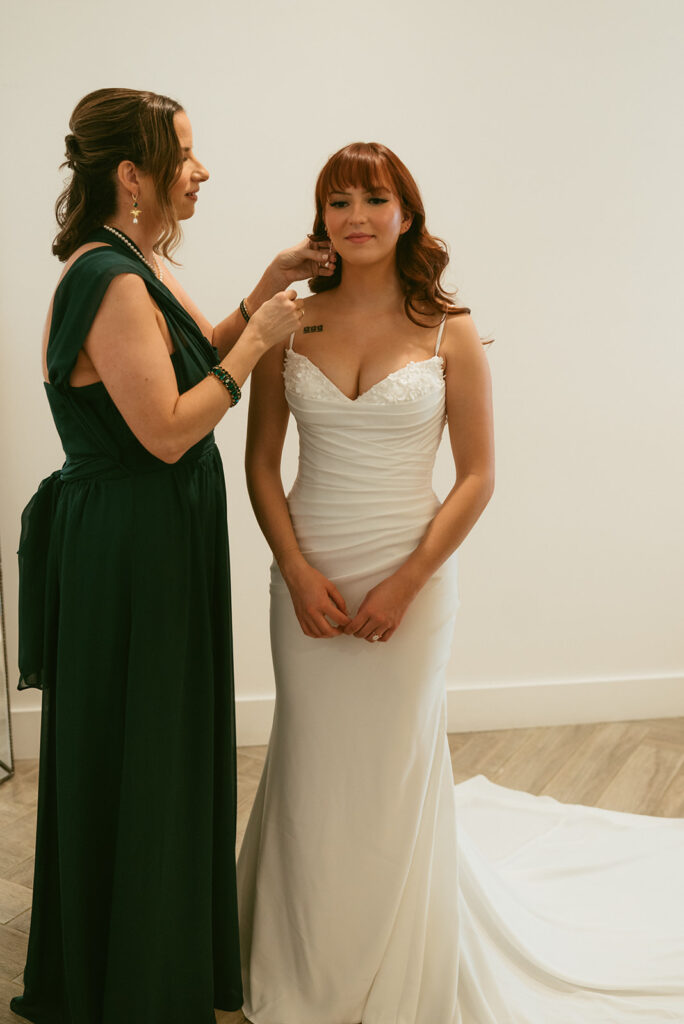 mother of the bride helping her with her jewelry