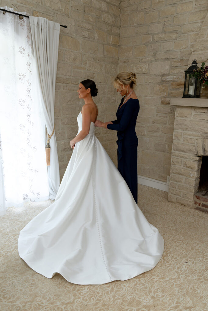 Mother of the bride helping her with the wedding dress