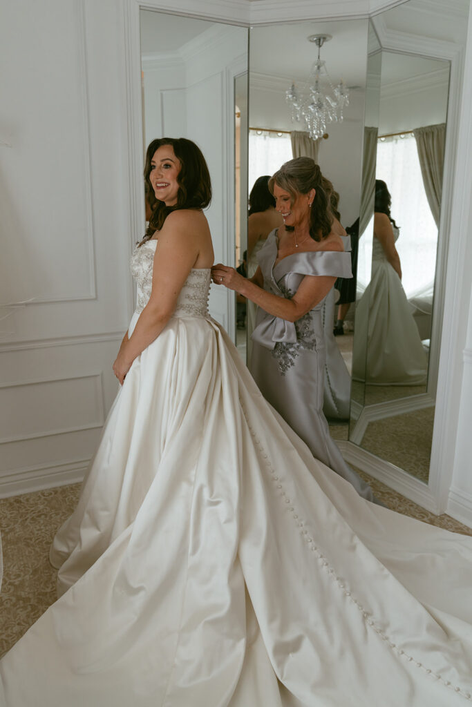 mother of the bride helping her with the wedding dress